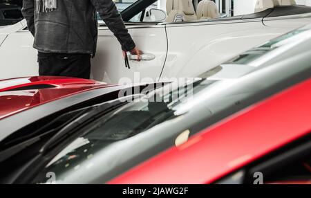 Un acquirente ricco alla ricerca di un nuovo Premium Luxury o di un'auto esotica all'interno dello showroom della concessionaria. Industria automobilistica. Foto Stock