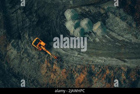 escavatore luminoso al lavoro su sfondo scuro da un drone Foto Stock