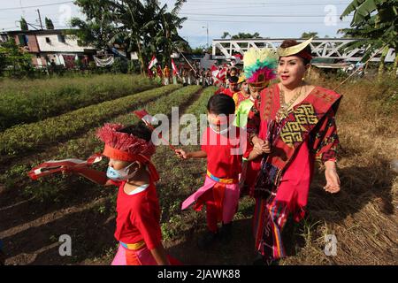 Jakarta, Indonesia. 01/06/2022, un certo numero di studenti che indossano abiti tradizionali provenienti da varie regioni sfilano intorno al villaggio dopo aver partecipato ad una cerimonia di bandiera per commemorare il compleanno di Pancasila, presso il cantiere della scuola di emergenza Kartini, sotto la strada a pedaggio Ancol, Jakarta, Indonesia. La Kartini Emergency School è gestita dai fratelli gemelli Rosy e Ryan, che accolgono studenti svantaggiati di vari gruppi senza dover pagare un centesimo. Anche se la loro scuola si trova alla periferia di sotto la strada a pedaggio e le piste dei treni, l'entusiasmo dei bambini coinvolti nella se Foto Stock