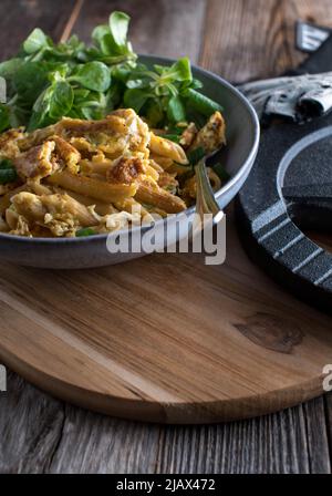 Pasto di allenamento per cena o pranzo con pasta di grano integrale fritta in padella, uova strapazzate e insalata verde servita su sfondo tavolo di legno con spazio copia Foto Stock