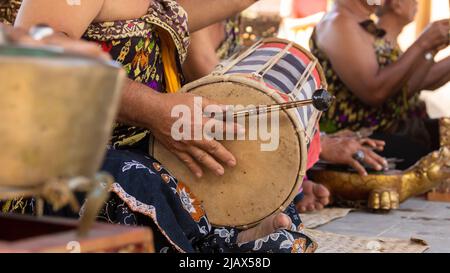 Un musicista suona un kendhang o ketipung, uno strumento tradizionale balinese, come parte di un ensemble musicale o di un gamelan, durante uno spettacolo Foto Stock