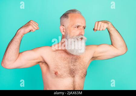 Profilo foto di sportivo stretto vecchio uomo mostra bicep look spazio vuoto indossare pantaloncini rosa isolato colore teal fondo Foto Stock