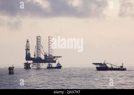 Piattaforme petrolifere con barca di rifornimento per il trasporto di persone o materiali a piattaforme vicine, South China Sea, Malesia Foto Stock