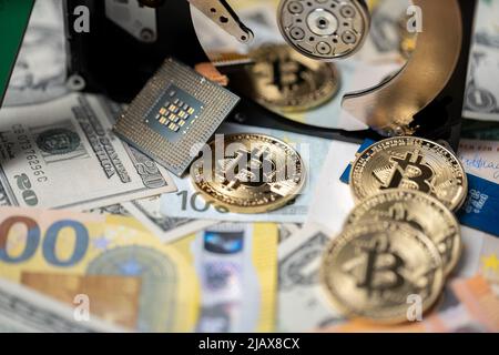 Crypto Mining Concept, bitcoin che si riflette nel disco rigido accanto alle banconote in dollari USA e alle banconote in euro. Hard disk con microprocessore, simbolo di grido Foto Stock