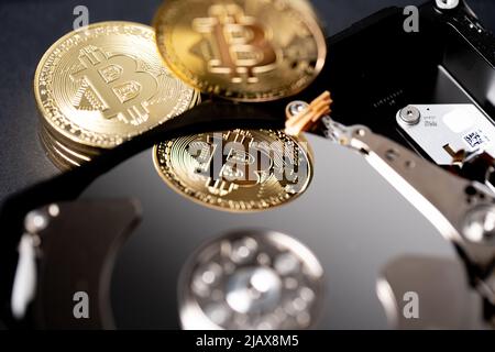 Bitcoin oro che si riflette sul disco rigido piatto di archiviazione. Concetto di valuta crittografica digitale e tecnologia blockchain Foto Stock