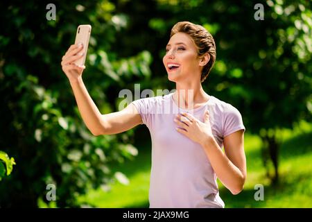 Ritratto di bella ragazza allegra passare del tempo su aria fresca prendendo selfie registrazione video all'aperto Foto Stock