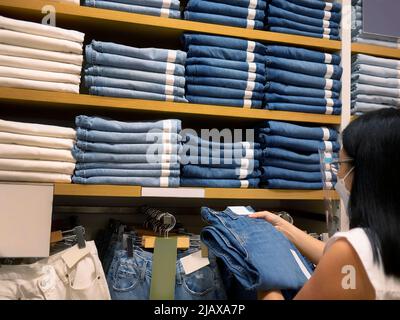 Una donna tailandese asiatica che indossa 2 strati di maschera medica usa e getta e visiera trasparente, shopping nel negozio di vendita al dettaglio durante l'epidemia di coronavirus. Foto Stock