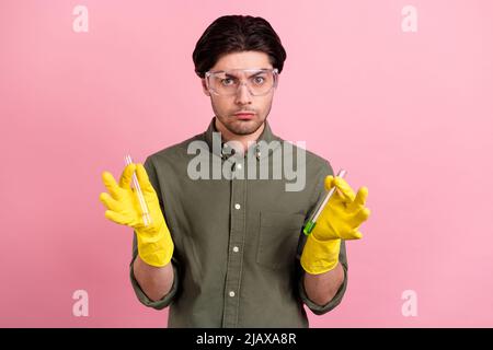 Foto di sicuro ragazzo tenere due tubo chimico indossare occhiali guanti khaki camicia isolato colore rosa sfondo Foto Stock