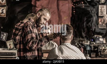 Uomo bearded in barbiere. Concetto di taglio dei capelli. Uomo in visita hairstylist in barbershop. Barbiere funziona con regolacapelli. Cliente hipster ottenere haircut Foto Stock