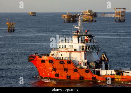 Piattaforme petrolifere con barca di rifornimento per il trasporto di persone o materiali a piattaforme vicine, South China Sea, Malesia Foto Stock