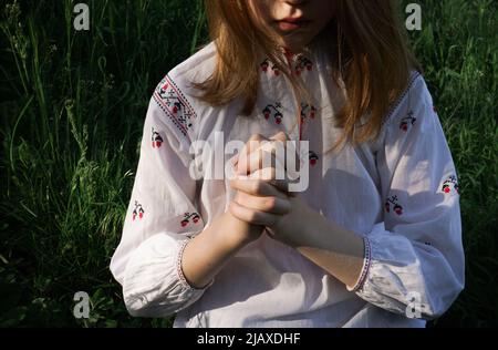 Una ragazza in camicia ricamata Ucraina sta pregando Foto Stock