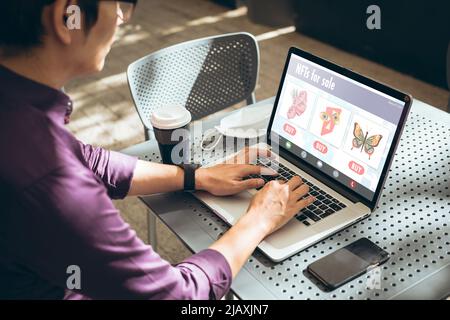 Giovane uomo d'affari asiatico che lavora su un computer portatile mentre si siede al tavolo in un caffè Foto Stock
