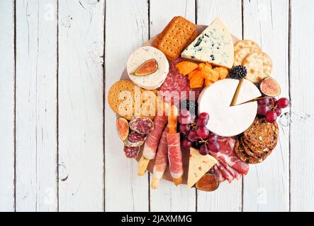 Piatto di salumi con diversi tipi di carni, formaggi e antipasti. Vista dall'alto su sfondo di legno bianco. Foto Stock