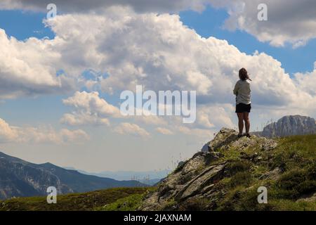 Una donna in cima ad una montagna che guarda la catena montuosa Foto Stock