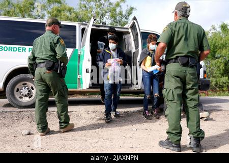 I migranti vengono trattenuti mentre vengono processati dalla pattuglia di confine degli Stati Uniti prima di prendere un autobus per un centro di detenzione il secondo giorno dell’attuazione della “credibile Fear and Asylum Processing Interim Final Rule”, il 1 giugno 2022 a la Joya, Texas, USA. La regola prevede che i casi che possono beneficiare dell'asilo siano accelerati in mesi anziché in anni, nel tentativo di alleviare il ritardo dei casi in tribunale. Il titolo 42, il mandato dell’era Trump che era stato fissato per impedire ai migranti di entrare negli Stati Uniti, doveva scadere il 23 maggio ma era stato bloccato da una causa intentata da diversi stati che citavano che la mossa t Foto Stock