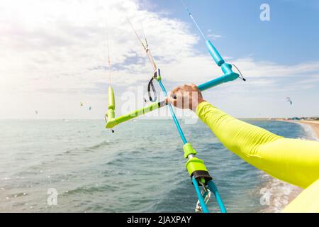 Giovane adulto caucasico fit uomo regolare kite surf board bar in sole uv protezione tuta in giornata di sole luminoso contro il cielo blu in mare o mare riva Foto Stock