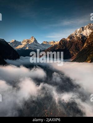 nebbia nella valle tra le montagne che si affacciano sul bel cielo Foto Stock