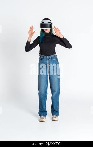 La teen girl che utilizza il visore vr è in realtà virtuale sfondo bianco futuristico cyberspace. Il concetto di metaverse, realtà virtuale, sociale virtuale Foto Stock