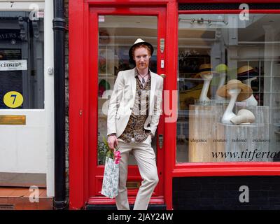 Richmond, Greater London, England, maggio 18 2022: Signori alla moda con capelli rossi e una barba che indossa un cappello e che trasportano fiori pone all'esterno di un negozio di cappelli Foto Stock