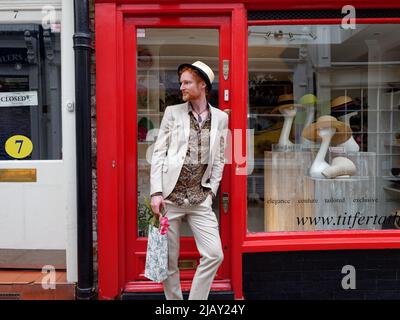 Richmond, Greater London, England, maggio 18 2022: Signori alla moda con capelli rossi e una barba che indossa un cappello e che trasportano fiori pone all'esterno di un negozio di cappelli Foto Stock