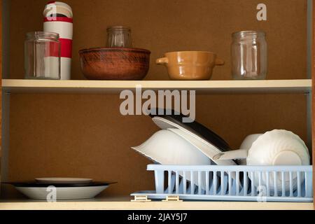 Vecchio armadietto della cucina con gli utensili nella cucina nell'appartamento, i piatti della cucina sui ripiani nel mobile Foto Stock