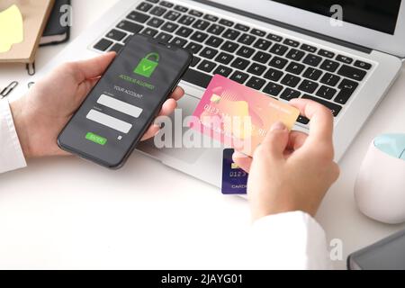 Giovane donna con carta di credito utilizzando smartphone moderno per il pagamento online, primo piano Foto Stock