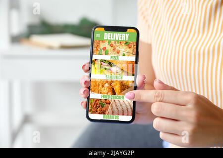 Giovane donna con smartphone che ordina cibo online, primo piano Foto Stock