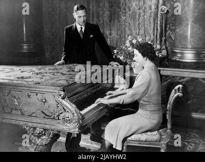 The Royal Silver Wedding -- H.M. la Regina, che è un pianista compiuto, suonando alcune delle sue canzoni preferite per H.M. il Re. Lunedì prossimo, 26th aprile, le loro maestà Re Giorgio VI e Regina Elisabetta celebrano il loro anniversario di matrimonio del 25th: Il loro matrimonio d'argento. Queste intime fotografie mostrano la coppia reale a casa nei loro appartamenti privati a Buckingham Palace, Londra, e sono state scattate appositamente per l'occasione. Aprile 20, 1948. (Foto di Fox Photos). Foto Stock