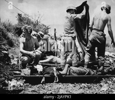 Aiuto per i feriti su Okinawa -- le truppe ferite su Okinawa sono date il primo aiuto ad una stazione di andata. I corpsmen hanno strung un filo per tenere le bottiglie di plasma di anima. Maggio 30, 1945. (Foto di stampa associata). Foto Stock