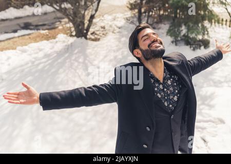 L'uomo barbuto latino gioiva e girava intorno guardando la macchina fotografica all'esterno in inverno. Foto di alta qualità Foto Stock