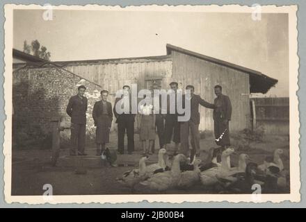 Una giovane donna e uomini in posa sullo sfondo di un edificio in legno a Bucarest sconosciuto Foto Stock