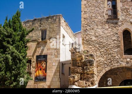 28 maggio 2022, Tarragona, Catalogna, Spagna: Un manifesto del festival Tarraco viva è visto sul muro di una vecchia casa. Tarraco (ora Tarragona) ha la più antica costruzione architettonica romana (2nd sec. a.C.) al di fuori dell'Italia. Il muro, alto 6 metri e spesso 4,5 metri, misurava all'epoca circa 3.500 metri. Oggi solo 1.100 m di mura e un cancello originale rimangono e circondano la parte vecchia della città.dopo due anni della pandemia del convivio-19 durante la quale i ricavi del turismo sono scesi, la città di Tarragona ha annunciato un raddoppio della sua capacità di nave da crociera nel 2021. La città beneficia di f Foto Stock