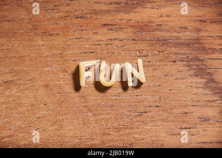 Divertimento di parola formato con lettere di pasta della minestra dell'alfabeto su uno sfondo di legno. Foto Stock