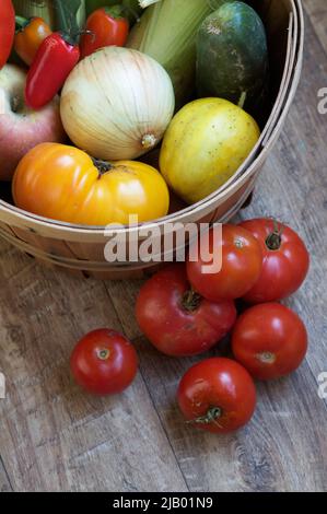 Un cestino pieno di prodotti freschi maturi, tra cui pomodori, cipolle e peperoni della raccolta autunnale presso uno stand agricolo locale a Washington, USA. Foto Stock