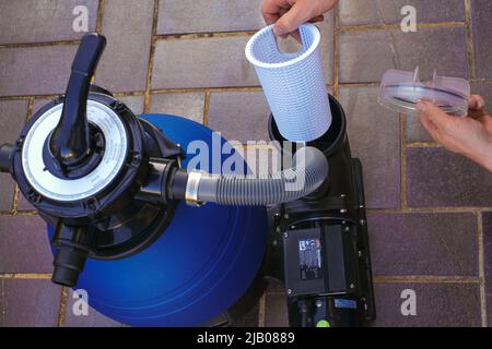 Filtro pool. Piscina pulizia equipment.Blue filtro acqua sulla terrazza vicino alla casa.man sposta i tubi al filtro nel primo piano piscina. Foto Stock