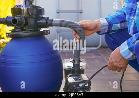 Filtro pool. Attrezzature per la pulizia della piscina sulla terrazza vicino alla casa.man sposta i tubi al filtro nel primo piano della piscina. Foto Stock