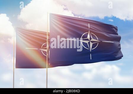 Cielo azzurro soleggiato e bandiere della nato e della nato Foto Stock