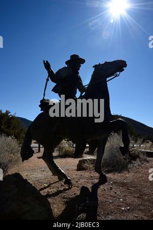 Una scultura in bronzo di un cowboy a cavallo si staglia contro il sole del pomeriggio a Santa Fe, New Mexico. Foto Stock