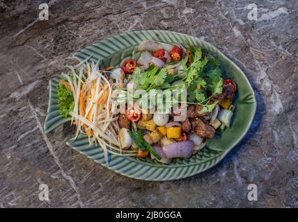 Friggere le costolette di maiale fritte e l'aglio sott'aceto, servite con le carote grattugiate e i coriandri di papaie grattugiate. Vista dall'alto, fuoco selettivo. Foto Stock