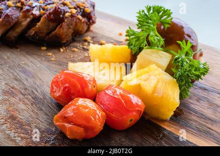 Arrostire pomodori, fette di ananas e purè di patate su un piatto di legno. Foto Stock