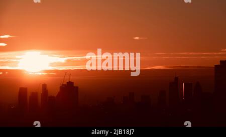 Vista aerea dell'alba sullo skyline di Londra con silhouette scraper contro un brillante e vivace cielo arancione. Foto Stock