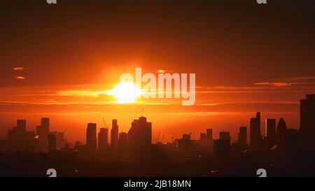 Vista aerea dell'alba sullo skyline di Londra con silhouette scraper contro un brillante e vivace cielo arancione. Foto Stock