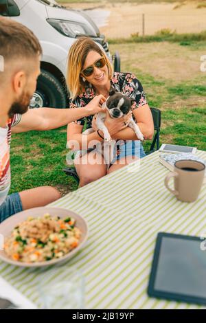 Donna sorridente che abbraccia il cane e l'uomo carezzandolo Foto Stock