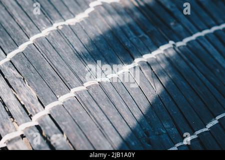 Vecchio tappeto di bambù tessuto, ruvido tessuto sporco, frammento banner. Linee verticali orizzontali diagonali, ombra a contrasto. Spazio di copia per il testo. Astratto Foto Stock