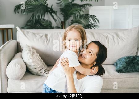 Una madre abbraccia dolcemente la figlia di quattro anni. Foto Stock