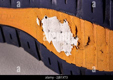 Closeup vecchia suola di scarpe rotta. La suola delle scarpe nell'immagine è gravemente usurata e presenta alcuni fori. Foto Stock