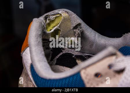 Primo piano vecchie scarpe rotte. La parte del tallone della scarpa nell'immagine è usurata e danneggiata. Foto Stock