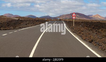 Strada vuota con cartello stradale a sinistra in paesaggio vulcanico a Lanzarote. E 'la strada per l'attrazione turistica Los Hervideros Foto Stock