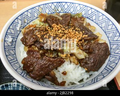 Il primo piano Yakiniku Don, carni di manzo alla griglia (yakiniku) condito con una ciotola di riso (donburi) con salsa yakiniku, nel ristorante locale in Giappone. Foto Stock