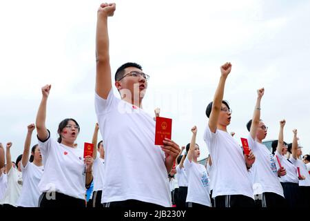 ZHANGYE, CINA - 2 GIUGNO 2022 - più di 1470 18 anni, tre studenti anziani della scuola media di Zhangye giurano solennemente il pugno di destra sul playg Foto Stock